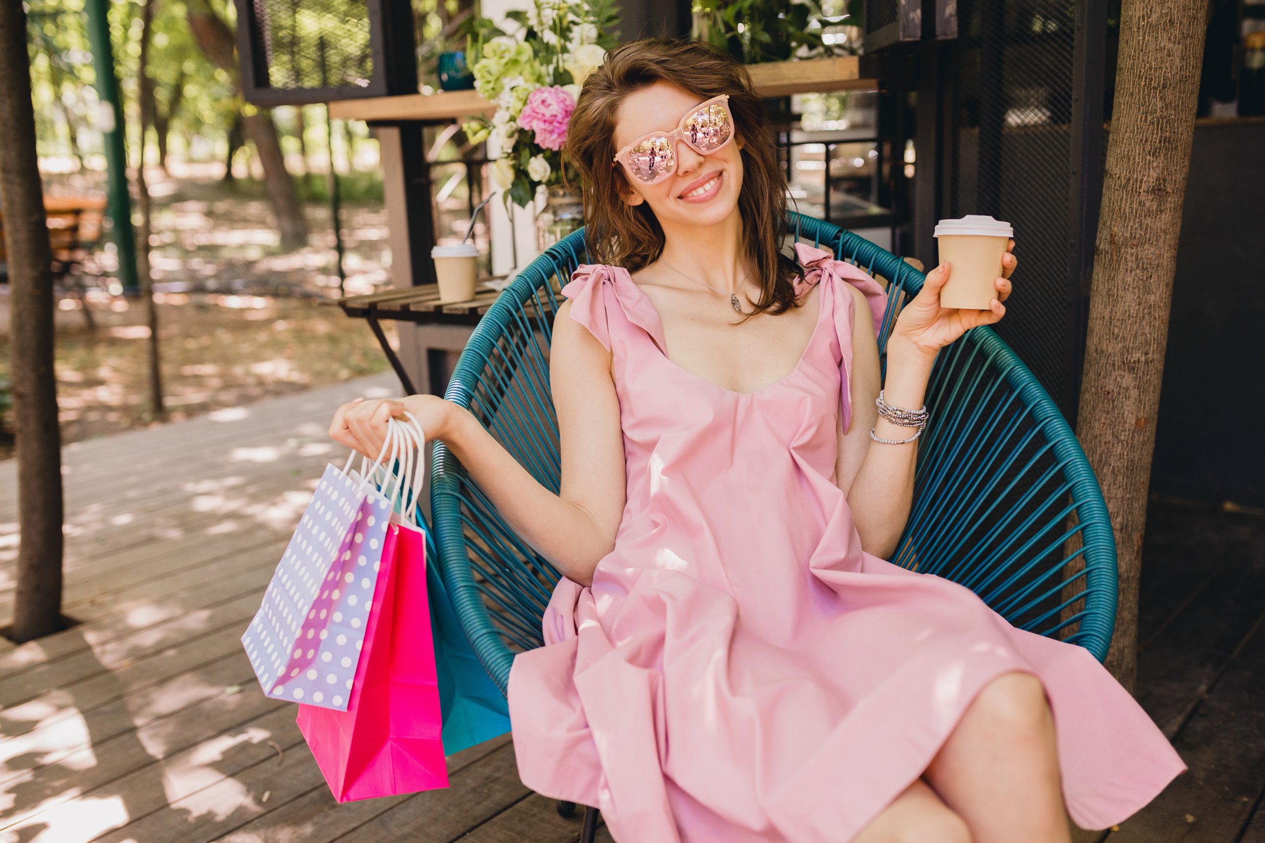 portrait young smiling happy attractive woman sitting cafe with shopping bags drinking coffee summer fashion outfit pink cotton dress trendy apparel scaled
